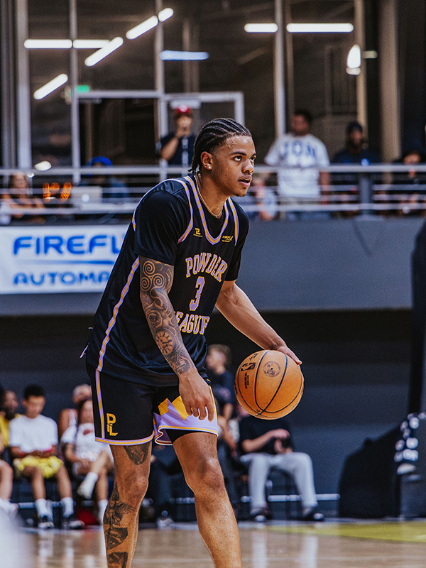 NBA Utah Jazz player Keyonte George in a jersey with FireFly Automatix logo and signage behind him, holding a basketball on a court